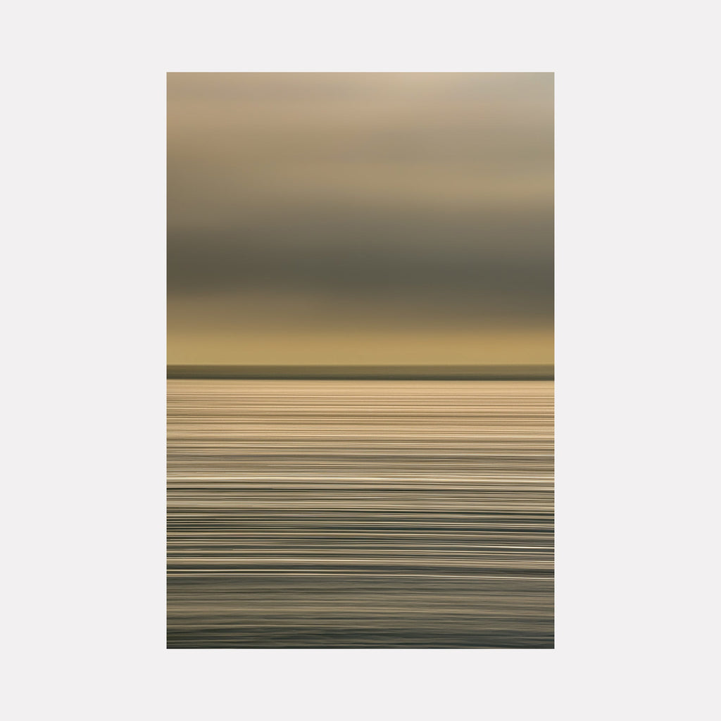 The artwork "Sun Streaks On The Atlantic" by Neil Shapiro features a minimalist seascape with layered horizontal lines in muted gold, gray, and soft beige tones. The subtle gradation and textured brushstrokes evoke the serene atmosphere and calm motion of the Atlantic, reminiscent of Mark Rothko’s color field and Agnes Martin’s restrained, meditative abstraction.