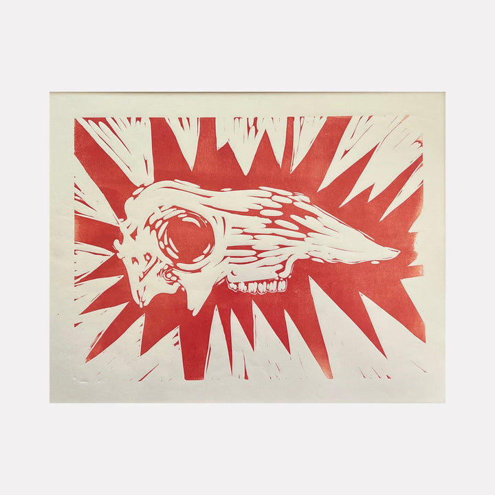 The artwork "Southern Highway" features a stylized animal skull with intricate bone details, set against a bold red background with jagged radiating spikes. The texture suggests a woodcut or linocut print, emphasizing sharp contrasts and dynamic shapes. This piece by Ashley Ranae Quick captures a rustic, raw aesthetic.