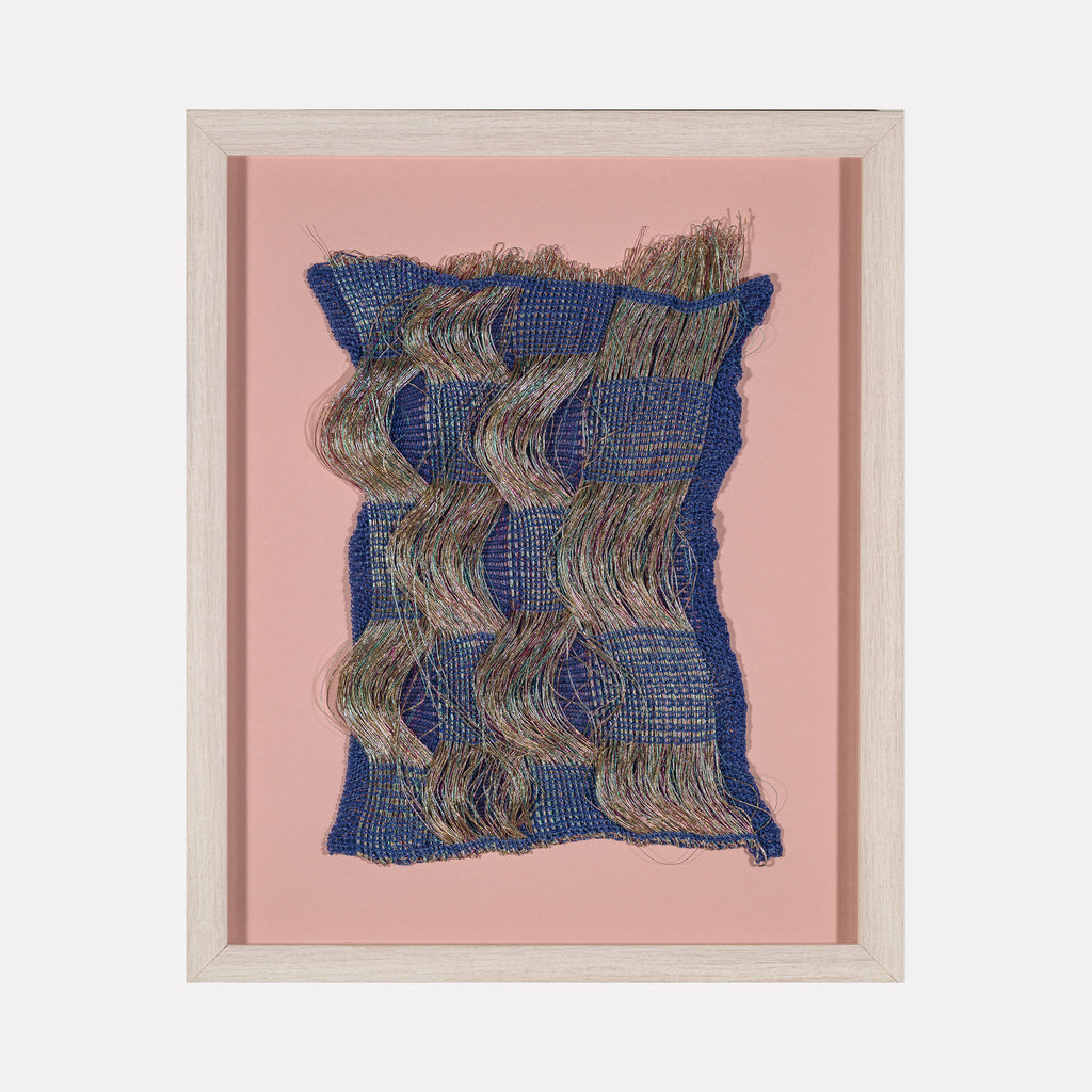 Time Streams (#1) by Craftwork presents a woven textile art piece with undulating multicolored threads set against a deep blue base, framed in light wood and mounted on a soft pink background, blending tactile texture with fluid motion in a contemporary art style.