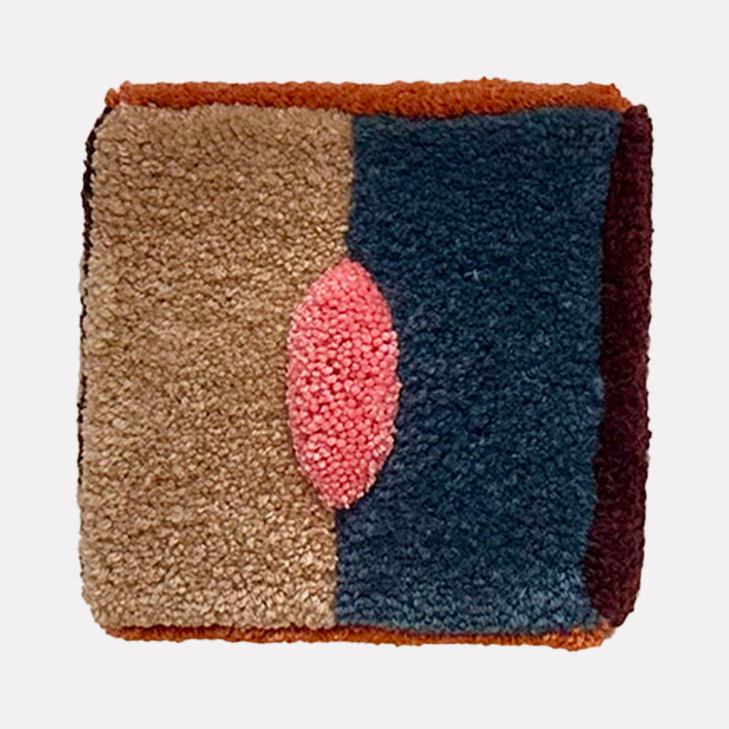 The artwork "Untitled" features a textured, rectangular design with a central oval shape in vibrant pink. It is divided into distinct color blocks of beige, deep blue, rust, and dark burgundy, showcasing a rich, tactile fabric composition with a cozy and plush appearance. By Ana Maria Farina.