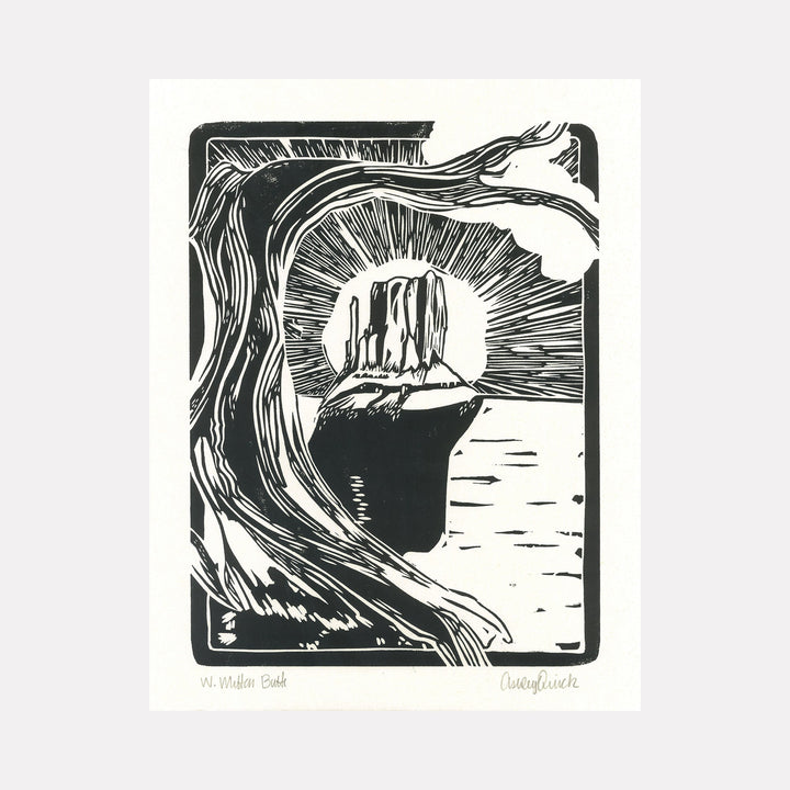 The artwork "West Mitten Butte" features a bold black and white linocut style depicting a towering rock formation framed by a curving tree branch in the foreground. The textured lines radiate from the butte, creating a dramatic contrast and sense of depth. This minimalistic landscape print by Ashley Ranae Quick captures the rugged beauty of nature.