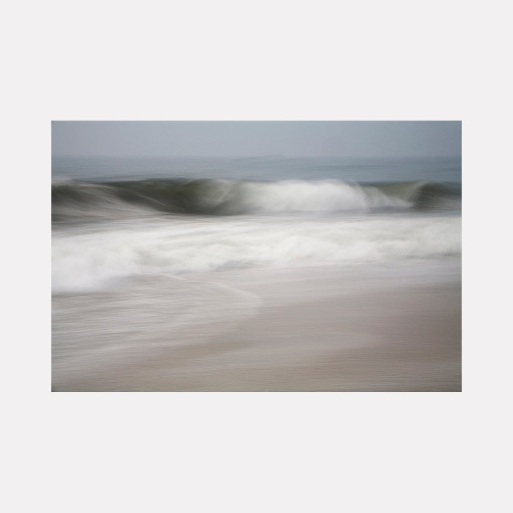 The artwork "A Gentle Wave" by Sandi Daniel features a serene seascape with soft, blurred waves in muted blues, grays, and whites. The gentle motion and subtle textures evoke a peaceful, contemplative mood reminiscent of the atmospheric abstraction found in works by Gerhard Richter and Hiroshi Sugimoto.
