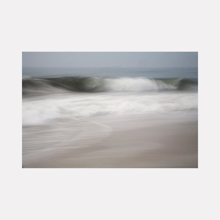 The artwork "A Gentle Wave" by Sandi Daniel features a serene seascape with soft, blurred waves in muted blues, grays, and whites. The gentle motion and subtle textures evoke a peaceful, contemplative mood reminiscent of the atmospheric abstraction found in works by Gerhard Richter and Hiroshi Sugimoto.