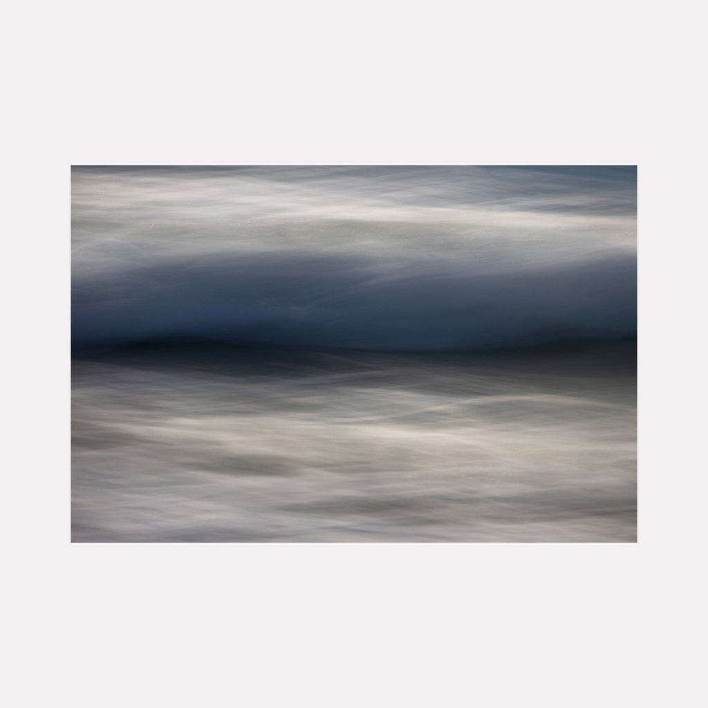The artwork "Ebb and Flow" by Sandi Daniel features a serene abstract seascape with smooth, layered waves in deep blues and soft grays. The textured, flowing forms evoke a sense of calm movement and natural rhythm, reminiscent of the atmospheric qualities found in works by Hiroshi Sugimoto and Mark Rothko’s subtle color transitions.