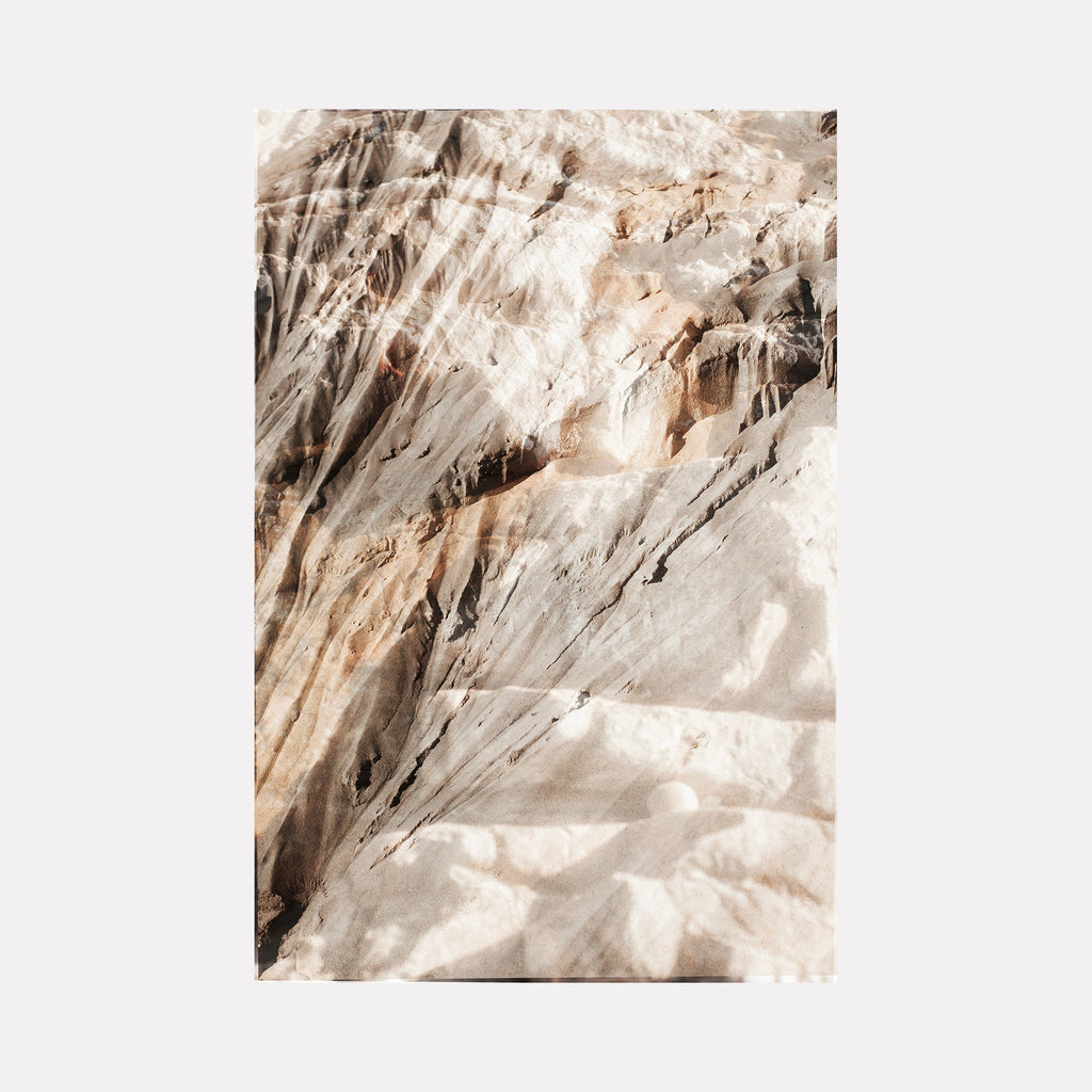 The artwork "erosion 7" by Eunice Pais captures an intricate close-up of layered rock surfaces in muted beige and sandy tones, revealing natural fractures and textured stratifications. The composition’s soft light and organic forms evoke the contemplative earth studies of Richard Long and the serene materiality found in Andy Goldsworthy’s works.