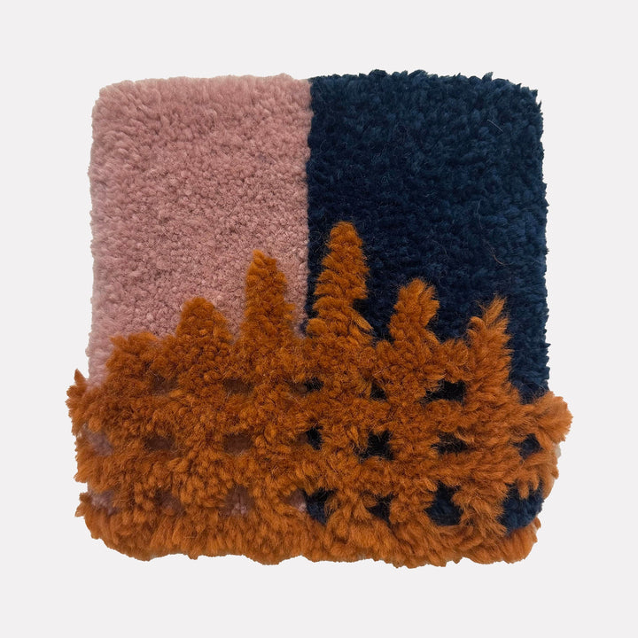 The artwork "Growth" by Ana Maria Farina features a textured, tufted design with a soft pink section on the left, a deep navy blue section on the right, and a raised, organic, burnt orange pattern overlaying the bottom half, creating a dynamic contrast of colors and tactile fibers.