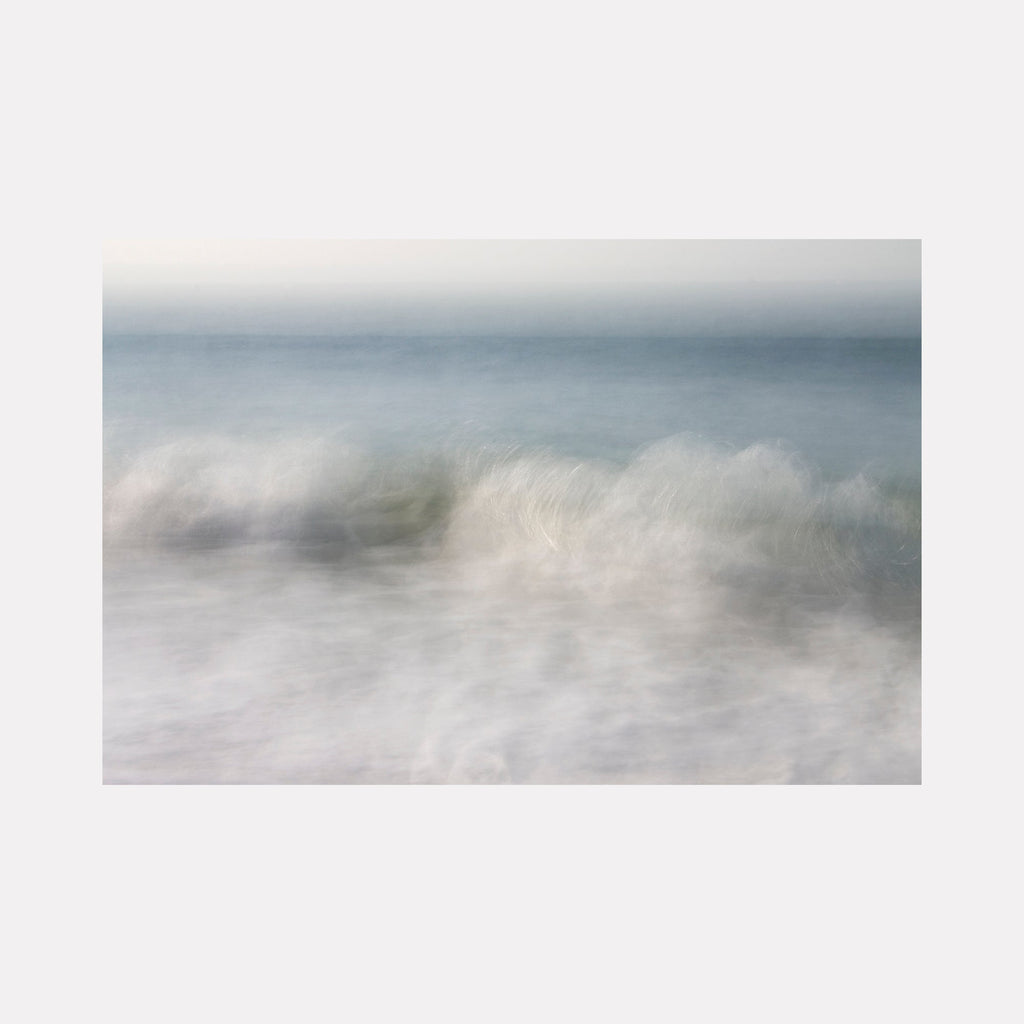 The artwork "Ocean Serenade" by Sandi Daniel features a serene seascape with soft, blurred waves rendered in muted blues, grays, and whites. The misty, atmospheric texture evokes a calming, ethereal quality, reminiscent of the lyrical abstraction and gentle palettes found in works by J.M.W. Turner and Hiroshi Sugimoto.