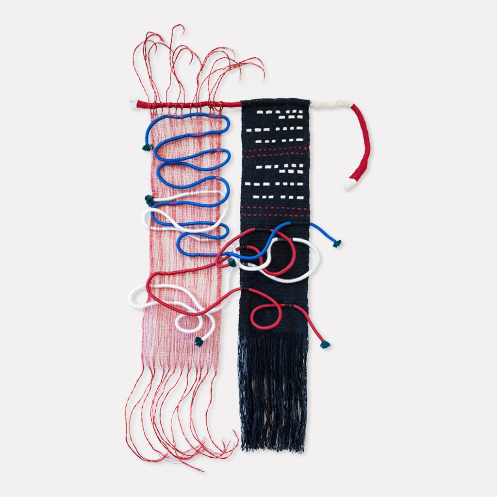 The artwork 'Svo-Bo-Dy! Russian Morse Code' by Kathie Halfin features a striking textile composition with contrasting red and black vertical panels, intricately woven with copper wire and nylon rope. Delicate loops and swirls of blue and red threads create a dynamic pattern against the textured cotton background, evoking the rhythmic nature of Morse code signals.