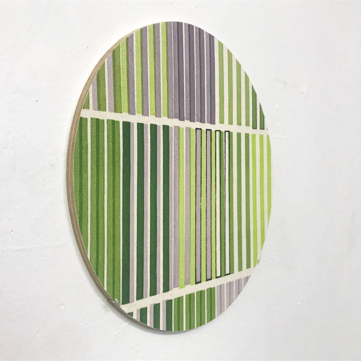 The artwork 'Line Study 3' features vertical stripes in varying shades of green and gray, intersected by horizontal white bands on raw silk. The minimalist geometric composition creates a rhythmic pattern mounted on birch in a circular format, measuring 10x10 inches. By Molly Koehn.