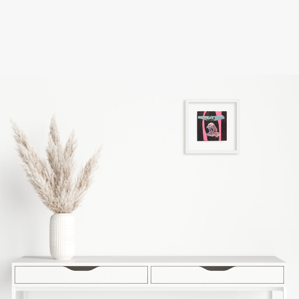 Artwork 'Fragment#08' by Winnie Sidharta features a mixed media composition displayed in a white frame against a white wall, showcasing vibrant pink and black magazine cutouts with watercolor elements. A 5x5 inch modern abstract piece set above a minimalist white console table adorned with dried pampas grass in a ribbed white vase.