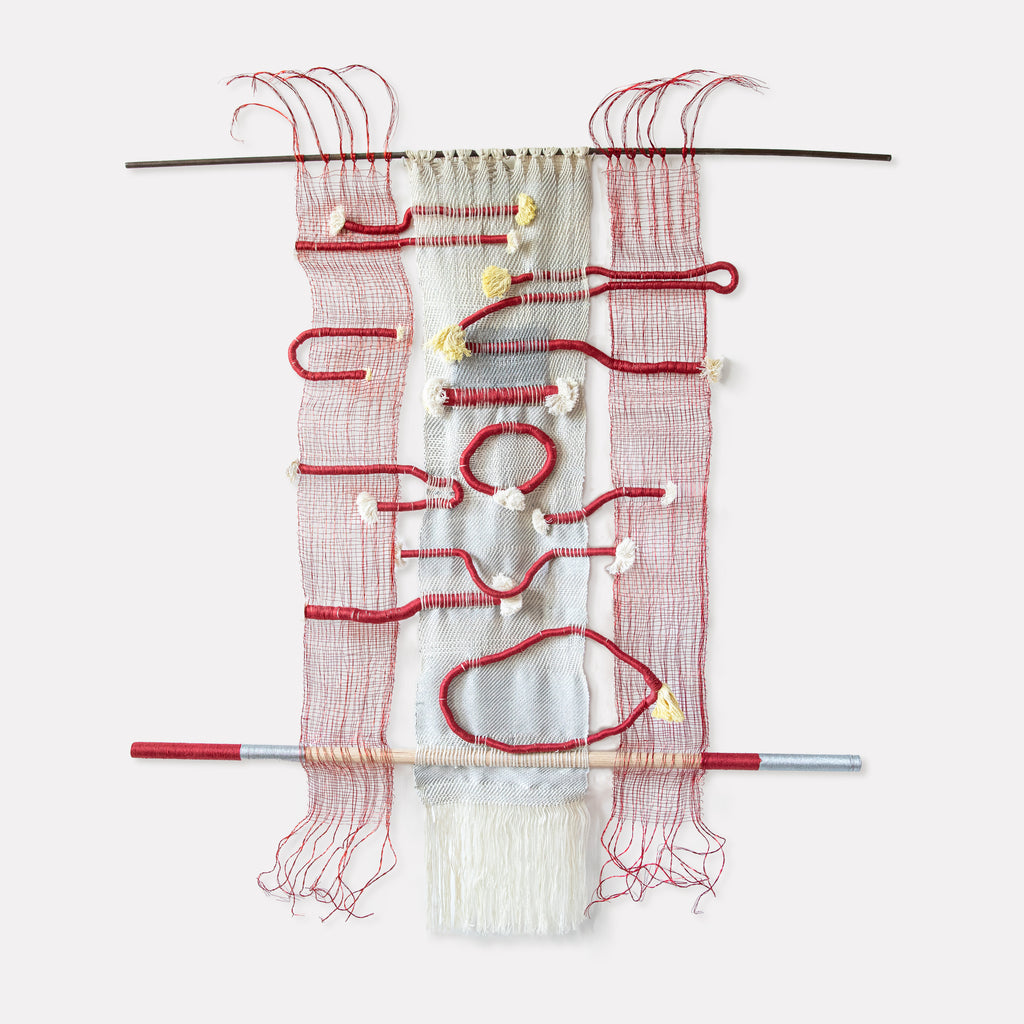 The artwork 'Hissing, Gurgling, Humming' by Kathie Halfin features a striking textile composition with red copper wire forming organic, fluid shapes against a white cotton background. The woven piece combines metallic floss yarn creating textural contrast, suspended between two horizontal rods, with delicate thread work and loose strands creating a sense of movement and rhythm.