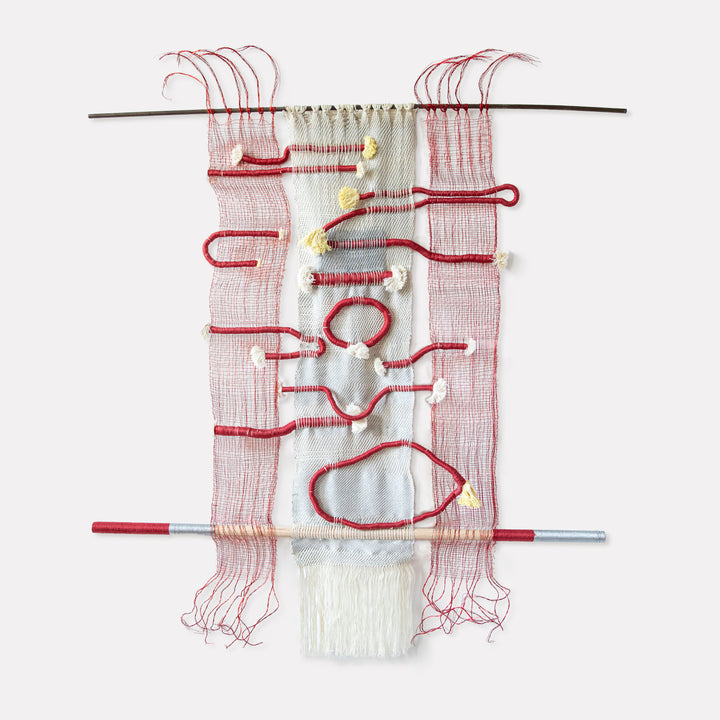 The artwork 'Hissing, Gurgling, Humming' by Kathie Halfin features a striking textile composition with red copper wire forming organic, fluid shapes against a white cotton background. The woven piece combines metallic floss yarn creating textural contrast, suspended between two horizontal rods, with delicate thread work and loose strands creating a sense of movement and rhythm.