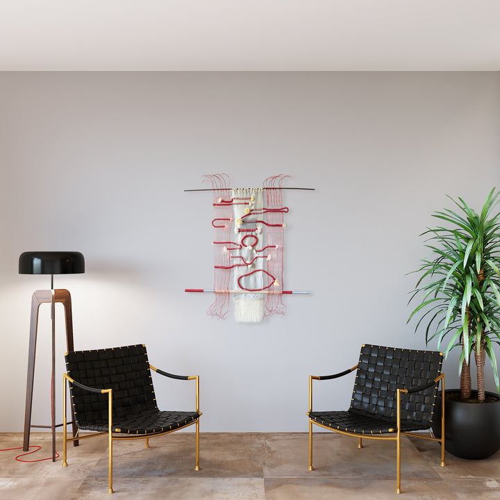 The artwork 'Hissing, Gurgling, Humming' by Kathie Halfin features an abstract wall sculpture combining copper wire and textile elements. Red and white vertical lines create dynamic movement, with interweaving metallic and cotton threads forming delicate patterns. The piece appears suspended against a light wall, its organic flowing design suggesting sound waves or musical notation.