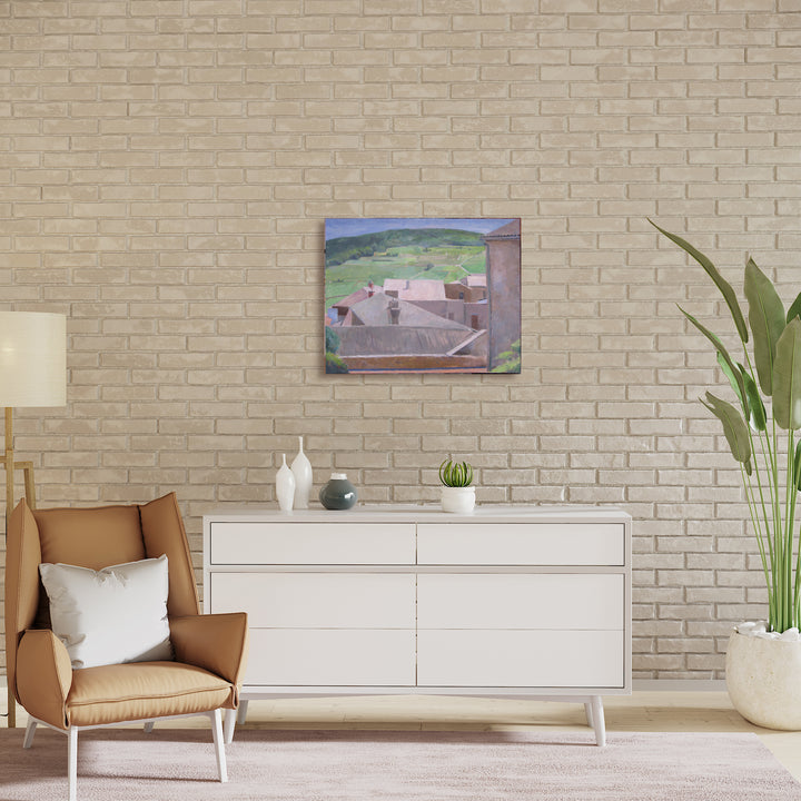 The artwork 'Solutre-Pouilly' by Peter Colquhoun features a serene countryside landscape with stone buildings nestled against rolling green hills. The oil on linen painting captures the rustic architecture with slate rooftops set against a muted blue sky, rendered in an impressionistic style with subtle earth tones and verdant hues. Artwork by Peter Colquhoun.