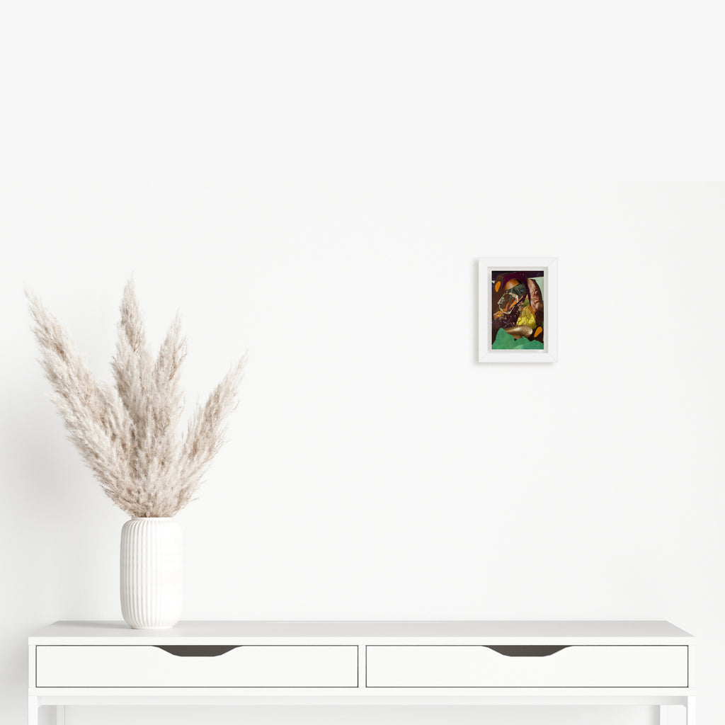 The artwork 'Fragment#12' by Winnie Sidharta features a framed mixed media composition in vibrant watercolors and magazine collage elements mounted on a white wall. Below sits a minimalist white console table with two drawers, adorned with a contemporary white ribbed vase containing fluffy beige pampas grass plumes.