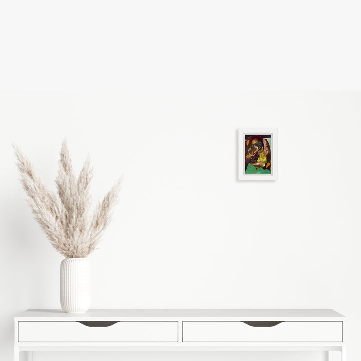 The artwork 'Fragment#12' by Winnie Sidharta features a framed mixed media composition in vibrant watercolors and magazine collage elements mounted on a white wall. Below sits a minimalist white console table with two drawers, adorned with a contemporary white ribbed vase containing fluffy beige pampas grass plumes.