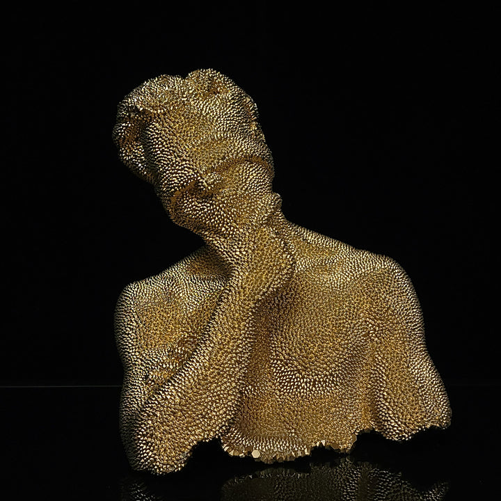 The artwork 'Thinking Blind - Original' by IvIvI features a gold-painted resin sculpture against a black background. The textured surface creates a mesmerizing dotted pattern across the form, capturing a contemplative pose. The 10-inch tall piece showcases elegant curves and a sophisticated metallic finish with intricate surface details, creating a striking contemporary art piece.