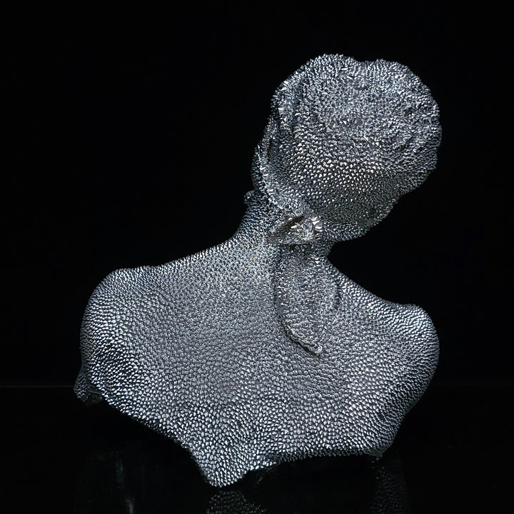 The artwork 'Thinking Blind - Original' by IvIvI features a silver resin bust sculpture with a distinctive textured surface composed of intricate dot patterns. Set against a black background, the metallic sculpture captures a contemplative pose, showcasing a minimalist yet dynamic design with a striking granular finish. 10x8x6 inches.