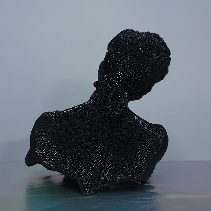The artwork 'Thinking Blind - Original' by IvIvI features a glossy black resin sculpture of a silhouetted bust in contemplative pose against a gray background. The textured surface creates a shimmering effect, capturing light across its dimensional form. This 10-inch contemporary art piece showcases elegant curves and a dramatic pose.