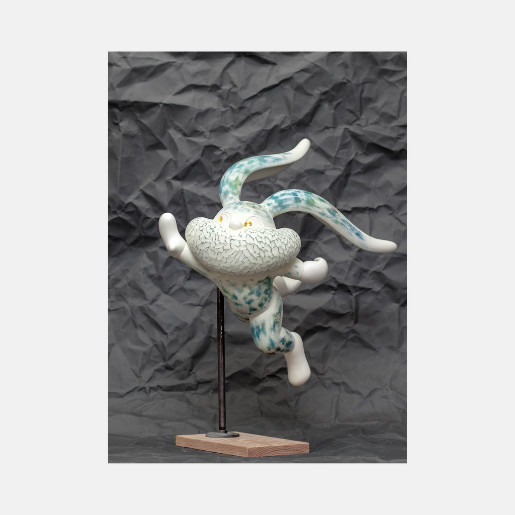 The artwork 'HOPE SPRINGS ETERNAL series' by Yusuke Ochiai features a dynamic resin sculpture of an abstract figure in motion, finished in white with turquoise speckled patterns. The textured surface combines spray paint and 22k gold leaf, mounted on a wooden base with metal support, creating a sense of weightless movement against a dark background.