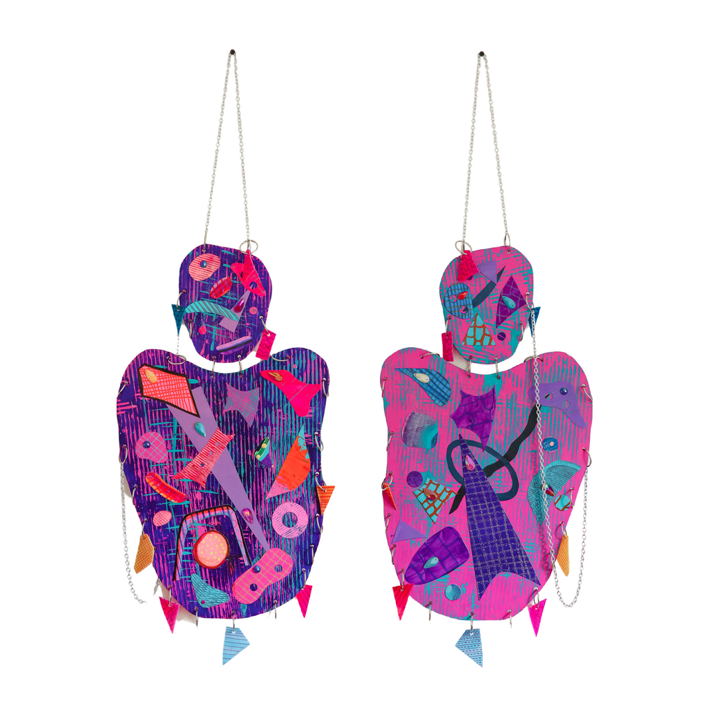 The artwork 'Christine (The Strawberry Girl)' features two vibrant hanging figures adorned with abstract geometric patterns in purple, pink, and coral tones. Each figure displays collaged musical motifs, interconnected chains, and decorative charms. The mixed-media piece combines acrylic paint with metallic accents and dimensional elements by Sunny Chapman.