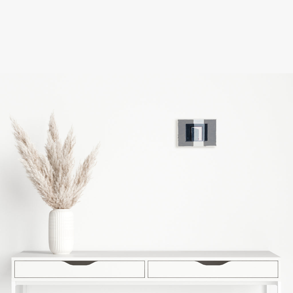 The artwork 'Closing Door 1' by Til Will features a minimalist acrylic painting on paper, depicting a partially open doorway in muted grays and blacks against a stark white surface. The small-scale piece captures a geometric architectural perspective, creating depth through subtle shadow play, measuring 5x7 inches - by Til Will.