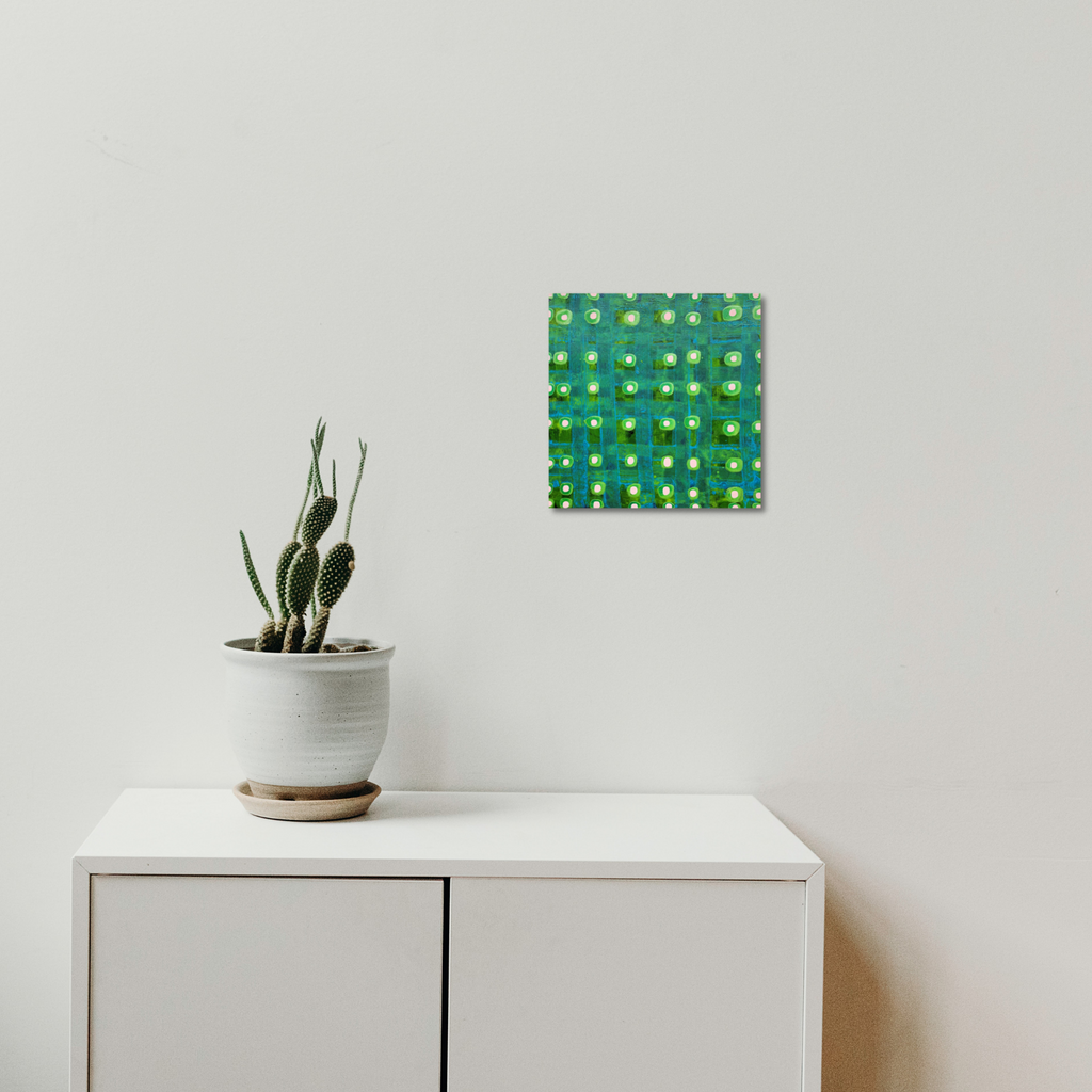 Composition No. 238 by Raul Ortiz features a vibrant geometric grid pattern in emerald green and turquoise hues with raised circular elements, mounted above a white cabinet with a potted cactus plant. The 12x12 inch acrylic on linen artwork creates a striking modern focal point against the minimalist white wall.