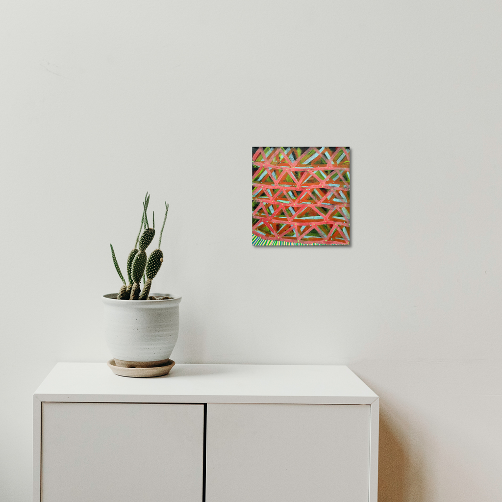 The artwork 'Composition No. 241' by Raul Ortiz features bold geometric triangular patterns in vibrant coral and green hues, creating dynamic intersecting lines on linen canvas. Mounted on a white wall above minimalist furniture with a decorative succulent plant, this 12x12 inch acrylic painting showcases a contemporary abstract design with precise linear composition.