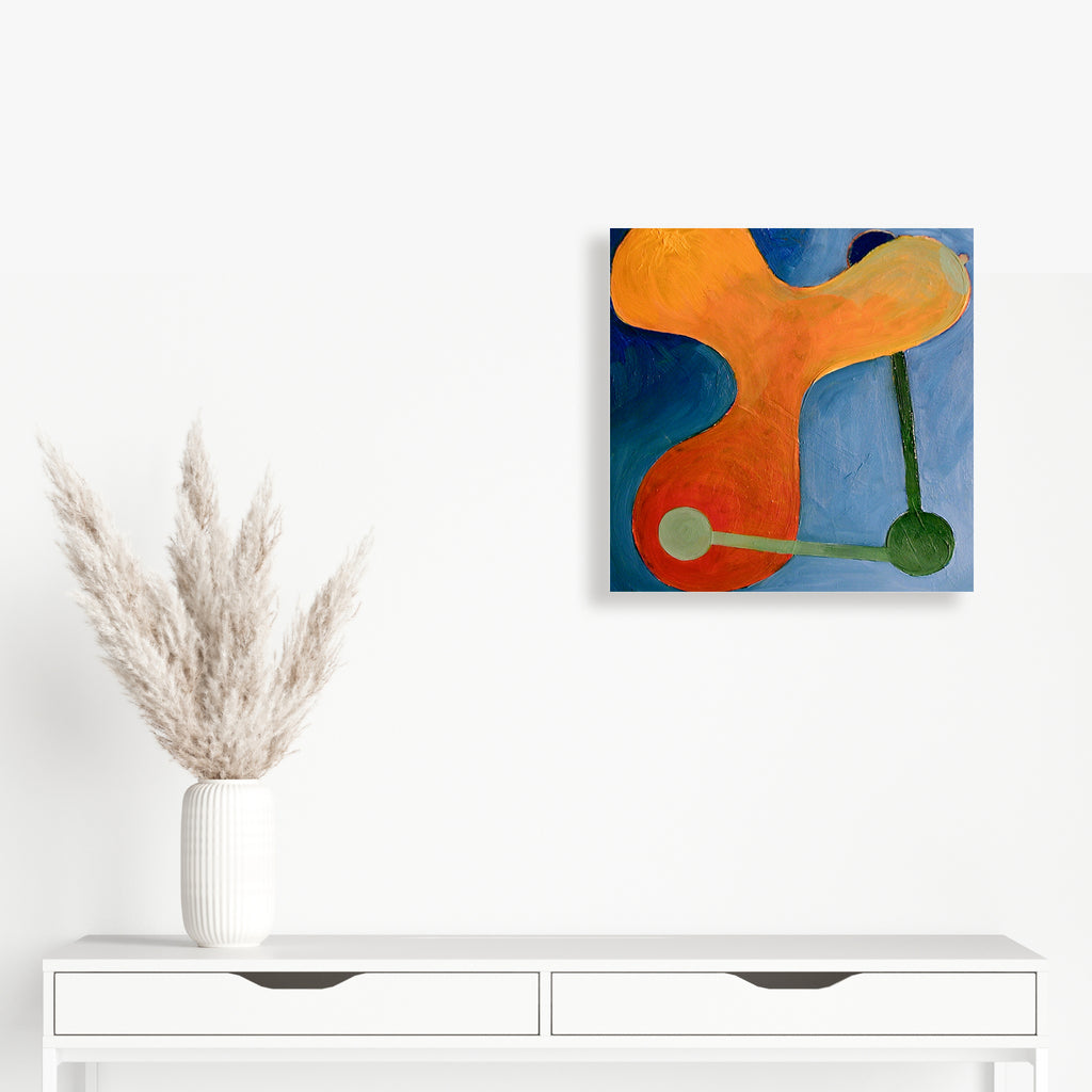 The artwork 'Constellation #2' by Fred Bendheim features an abstract composition with a vibrant orange curved form against a deep blue background. Two circular elements in sage green are connected by a thin vertical line, creating a dynamic balance between organic and geometric shapes in this 18x18 inch oil painting.