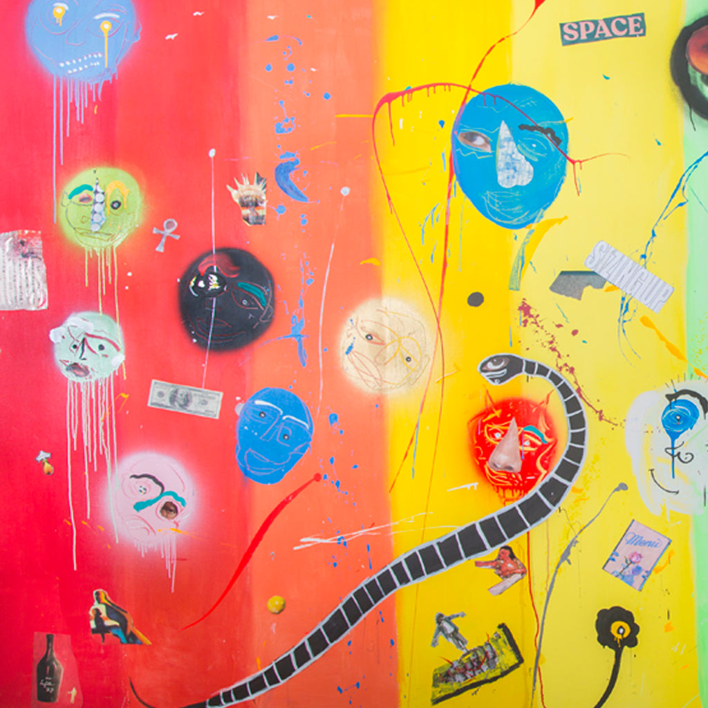 The artwork 'Des Balloons' by Cavier Coleman features vibrant abstract floating spheres with expressive faces against a split red and yellow background. A winding black striped path cuts through the composition, while dripping paint effects, paper collage elements, and scattered blue accents create dynamic movement. The mixed-media piece combines acrylic, enamel, and paper collage on canvas, showcasing a playful street art aesthetic.