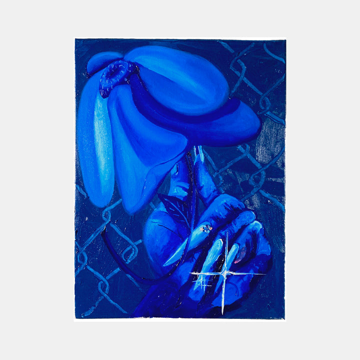 The artwork 'Flor en Mano' by Juan Arango Palacios features vibrant electric blue bananas floating against a deep navy background with geometric lattice patterns. The oil painting is adorned with sparkling rhinestones, creating a luminous effect. A stylized hand clutches the fruit, rendered in bold, modern brushstrokes and monochromatic blue tones.
