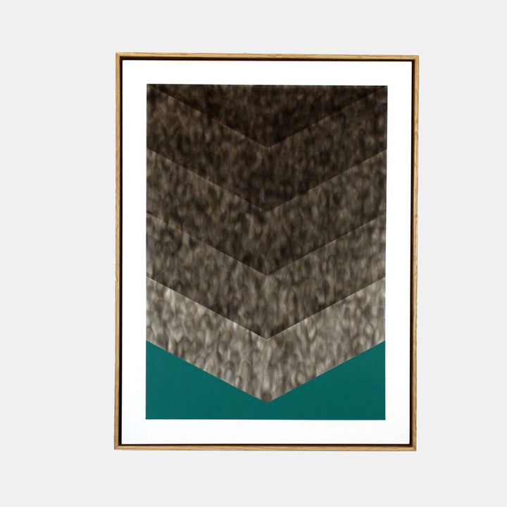 The artwork 'Foot Habits' by Evan Ishmael features a striking chevron pattern created with soot gradients, ascending from light to dark against a bold teal background. The textured, smoky effect creates depth through five distinct angular sections, framed in warm wood, showcasing the unique combination of soot and spray acrylic techniques.