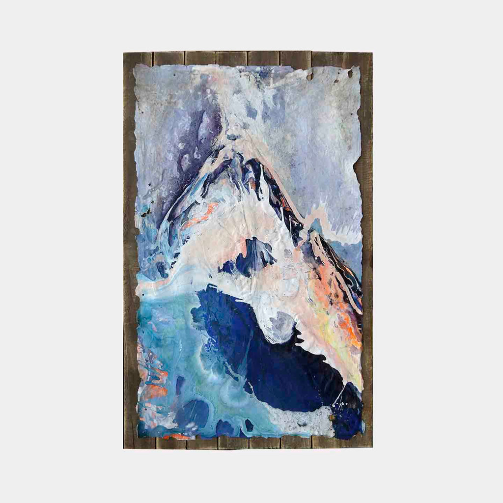 The artwork 'Haleakala' by Renee Phillips features a dramatic mountain peak rendered in ethereal blues, whites, and coral hues on burnt canvas. Abstract brushstrokes create a misty atmosphere around the peak, while deep navy shadows anchor the base. The textured acrylic and polymer composition is mounted on weathered beach wood, capturing the mystical essence of Hawaii's volcanic landscape.
