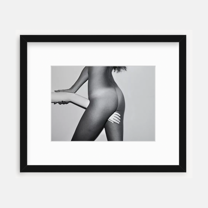 The artwork 'Hand in Between Legs' by Mari Sarai presents an artistic black and white photograph showcasing an abstract form with dramatic light and shadow. The composition features smooth contours and elegant lines, professionally matted and presented in a sleek black frame. The monochromatic technique enhances the sculptural quality and artistic expression.