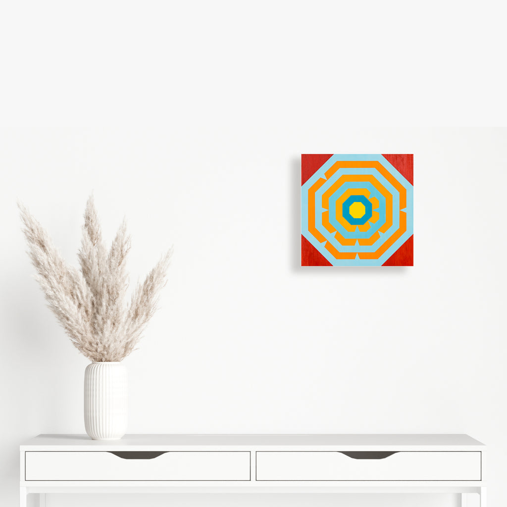 The artwork 'I Ching' by Amber Heaton features a vibrant geometric composition with concentric octagonal patterns in yellow and turquoise blue, set against a bold red background. The 12x12 inch acrylic painting on panel showcases precise linework and sharp color transitions, creating a modern interpretation of traditional I Ching symbolism.