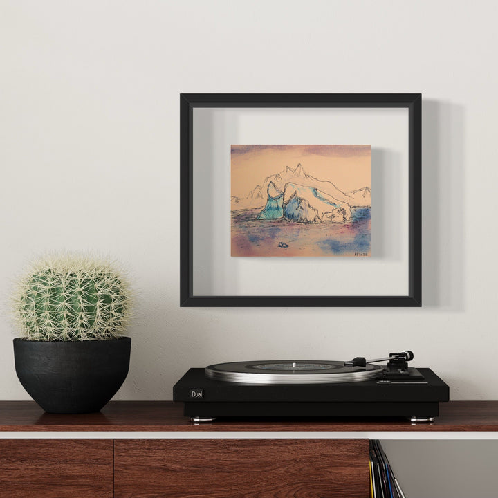 The artwork 'Iceberg_Half Moon Island' by Ali Ha captures a majestic Antarctic iceberg rendered in delicate blue and peach tones. The piece features sweeping ink lines depicting a glacial formation against a warm sunset sky, executed on Stonehenge archival paper with Micron ink and Caran d'Ache, displayed in a classic black frame.