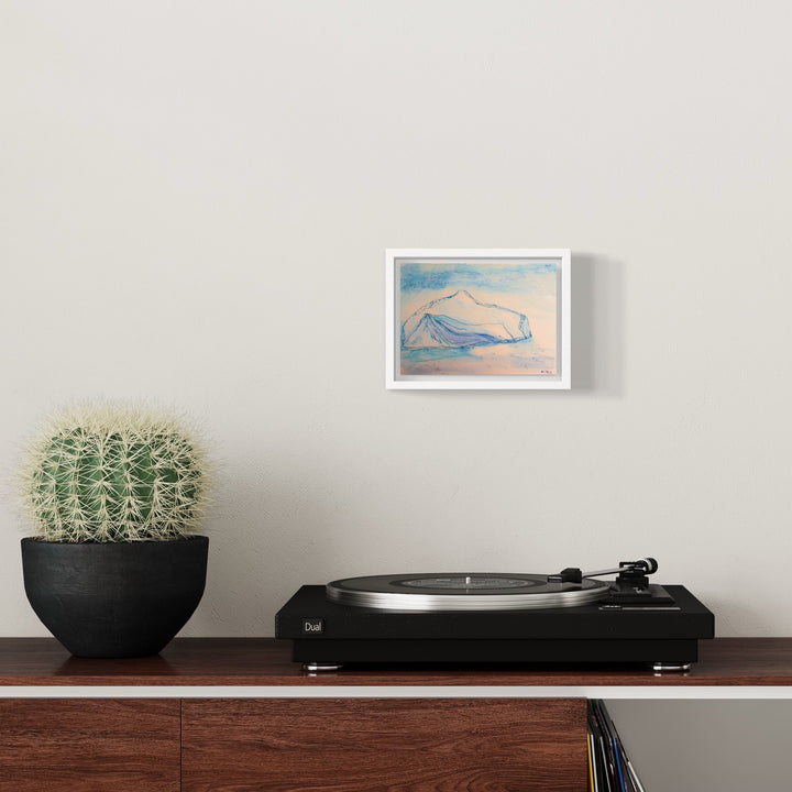 The artwork 'Iceberg_Base Brown' by Ali Ha features delicate line drawings of an iceberg formation in soft brown hues against a serene blue watercolor background, rendered on warm white Stonehenge paper. The minimalist composition captures the majestic form and subtle textures of floating ice in an abstract, ethereal style, framed in white.