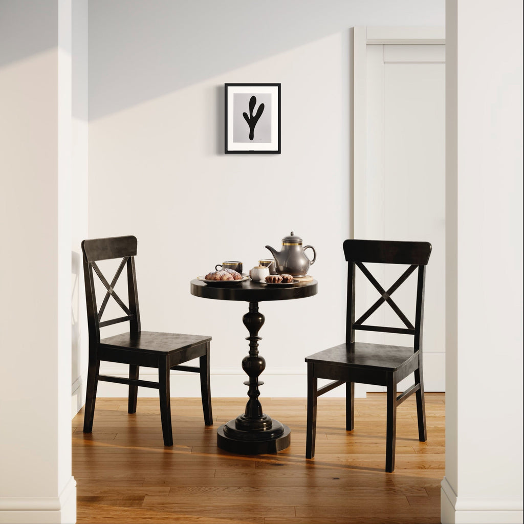 The artwork 'Morning Meditation XXII' by Shadia Sabagh showcases a minimalist tea setting with a black antique-style pedestal table and two cross-back chairs against a white wall. A framed black and white botanical print hangs above, while a vintage teapot and tea set rest on the round table. The scene is set on warm hardwood flooring, creating a serene breakfast nook atmosphere.