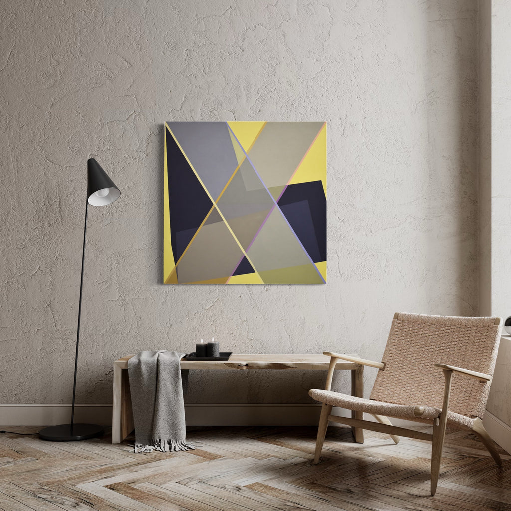 The artwork 'Staged X2' by Kati Vilim features a geometric abstract composition with intersecting triangular shapes in yellow, navy blue, and gray tones. Clean lines and sharp angles create a dynamic modern design on canvas over panel, displayed in a minimalist interior setting with textured walls and herringbone flooring. - Kati Vilim