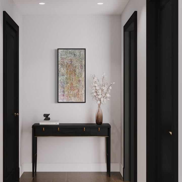 The artwork 'Number 16' by Roberto A Godinez features an abstract composition with textured layers in muted pastels and earthy tones, displayed in a black frame against a white wall above an elegant console table. The oil painting exhibits a weathered, multi-layered surface with subtle color variations, complementing modern interior decor. 36x18 inches framed artwork by Roberto A Godinez.