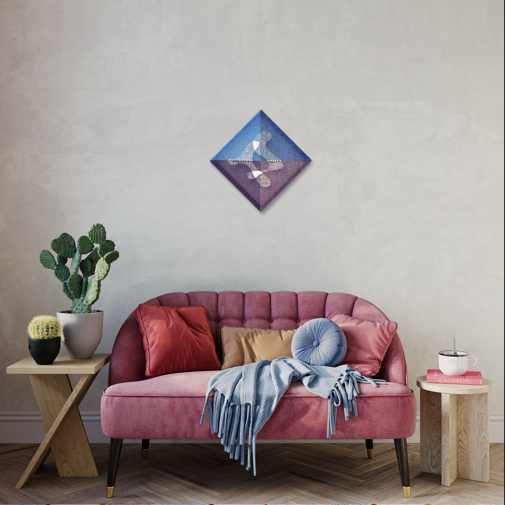 The artwork 'Flux' by Morgan Hale, a diamond-shaped handwoven linen and plaster piece, features a striking diagonal division of royal blue and rich purple hues, creating an abstract geometric composition. Showcased above a pink velvet sofa in a modern living space with complementary blue throw and decorative cactus.