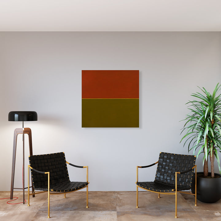 The artwork 'Humanity' by Shyun Song features a minimalist geometric composition with two bold horizontal blocks - a rust orange upper section and an olive green lower section - displayed on a pristine white wall. The modern oil painting creates a striking contrast against the contemporary interior setting with its clean, color-block aesthetic, measuring 40x40 inches.