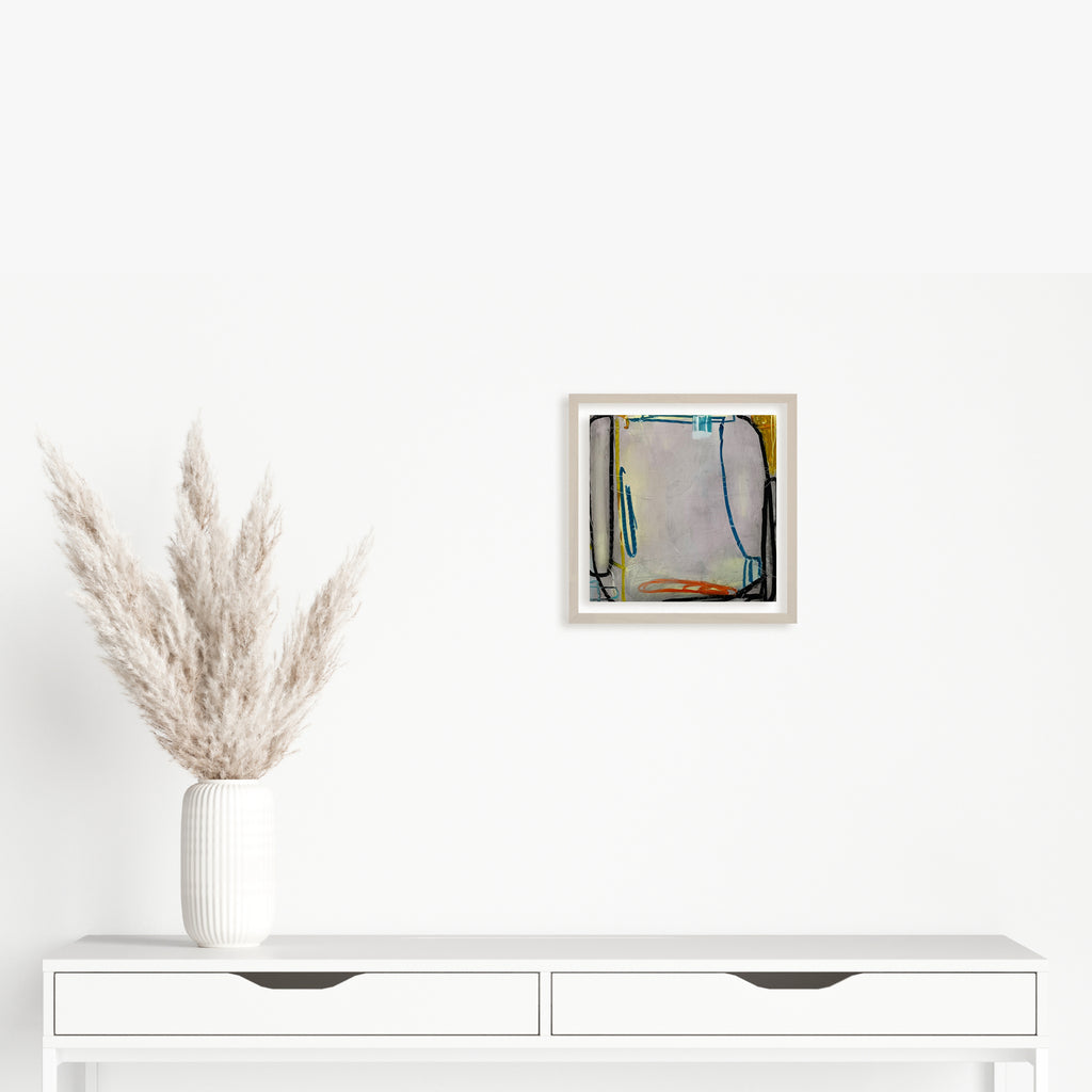 The artwork 'LS no. 17' by Janice La Motta features abstract geometric forms in soft grays and blues, with bold black linear elements framing the composition. Created with oil pastel on Yupo paper, the 9x9 inch piece displays a minimalist approach with subtle color transitions and organic lines, mounted in a clean white frame. by Janice La Motta