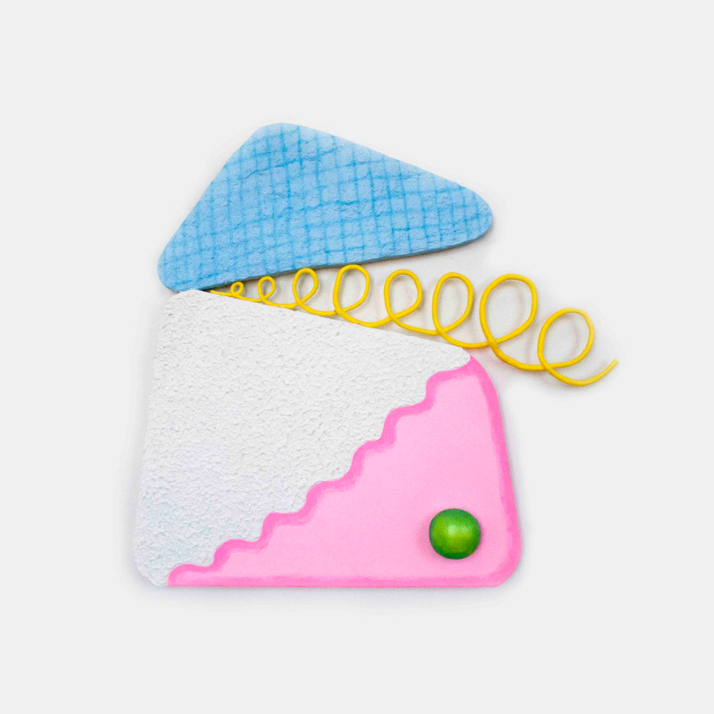 The artwork 'Loopy Cocktail Burp' by Ryan Patrick Martin features a geometric composition with a light blue triangular shape, a white textured block, and a pink scalloped corner accent. A vibrant yellow spiral wire emerges from the center, while a small green spherical element adds a playful touch. Mixed media construction combines wood, canvas, and epoxy clay with acrylic paint by Ryan Patrick Martin.
