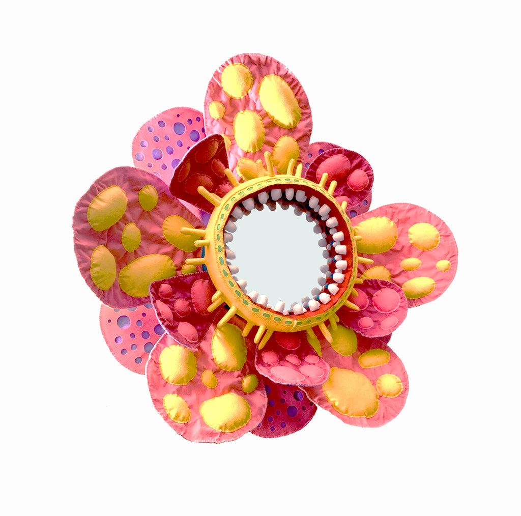 The artwork 'Love in Bloom' by James Hsieh features a vibrant mixed media flower with layered petals in coral pink and golden yellow hues. A circular mirror forms the center, surrounded by decorative spikes in orange. The petals showcase organic spotted patterns and fluid ink-like textures, creating a whimsical, abstract interpretation of a blooming flower.