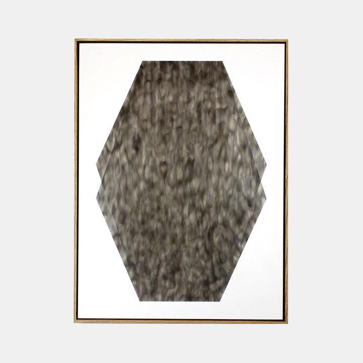 The artwork 'May Save Teeth' by Evan Ishmael features a striking hexagonal shape rendered in soot on panel. The textural composition displays varied shades of charcoal gray with organic, smoky patterns creating a weathered, abstract appearance. The geometric form contrasts boldly against a white background, framed in gold.