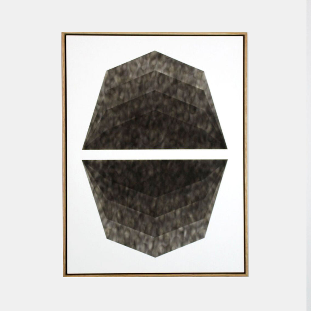 The artwork 'Mild Climate Needed' by Evan Ishmael features a striking geometric composition of split octagonal shapes rendered in rich charcoal soot on panel. The textured, smoky surface creates a dynamic contrast against white background, showcasing layered depths and angular patterns within a minimalist design. 24x18 inches. By Evan Ishmael.