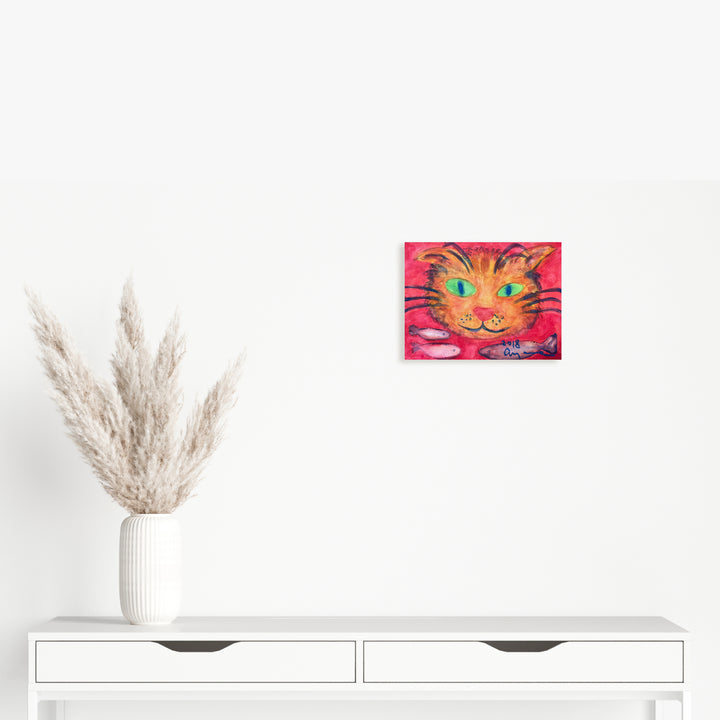 The artwork 'Naughty Cat' by Ayane Kurai features a vibrant close-up of a cat's face against a hot pink background. The feline's striking green eyes are emphasized with bold outlines, while orange and yellow tones create a playful, whimsical expression. Watercolor and cray-pas techniques blend to create texture and depth in this 9x12 inch piece.