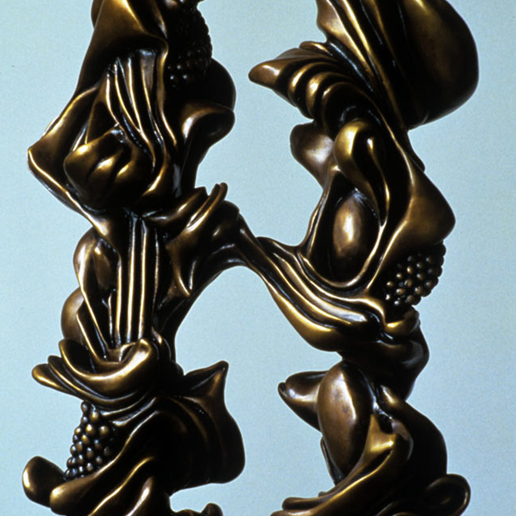 The sculpture 'NEXUS' by Nora Chavooshian features abstract flowing bronze forms creating dynamic curves and ridges against a pale blue background. The polished bronze surface exhibits rich golden-brown tones with intricate textural details including grape-like clusters and undulating ribbons. Standing 36 inches tall on a marble base, this elegant contemporary sculpture demonstrates masterful metalwork craftsmanship.