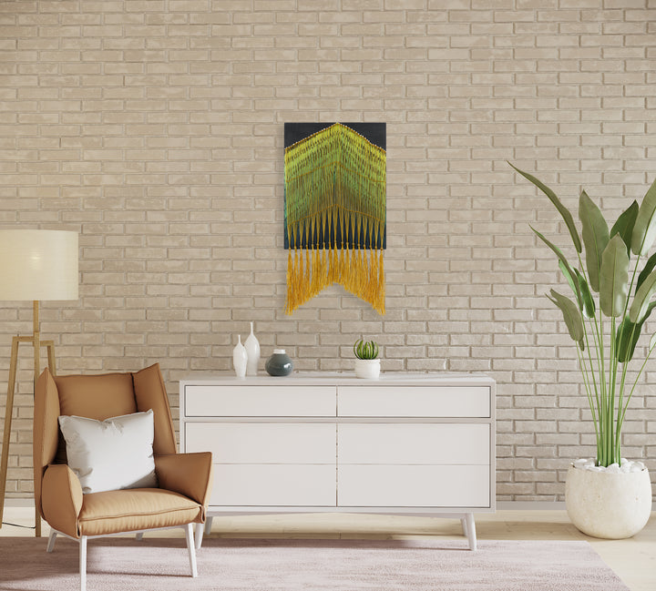 The artwork 'Night Forest' by Amber Heaton features a striking geometric wall hanging combining acrylic painting on wood with textile elements. Neon green and blue lines create a triangular forest canopy pattern, flowing into vibrant golden yellow cord tassels. The contemporary piece measures 22x12 inches, blending modern abstract design with traditional fiber art techniques.